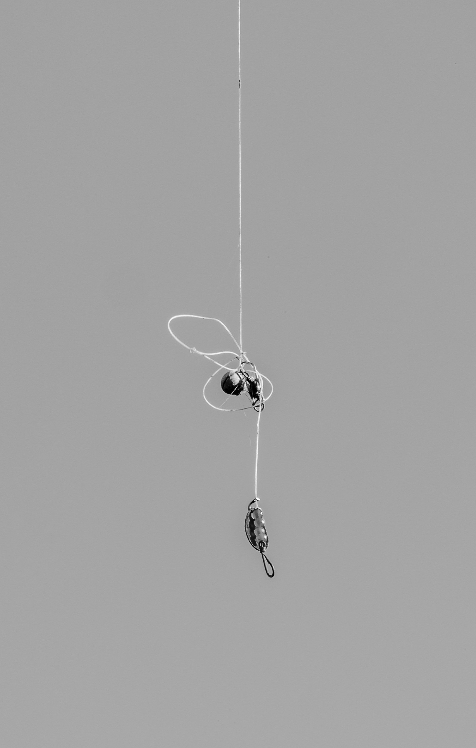 small fishing lure and two weights hanging from single strand of fishing line
